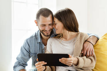 Happy affectionate couple with tablet at home - SBOF02181