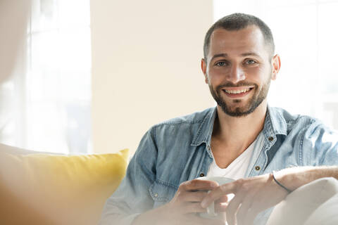 Porträt eines glücklichen jungen Mannes mit Kaffeetasse in der Hand, lizenzfreies Stockfoto