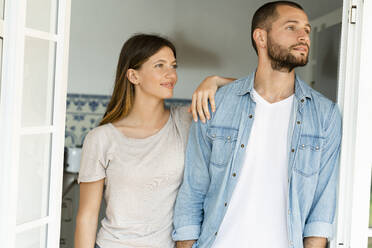 Attractive young couple standing in the door together at home and looking outside - SBOF02206