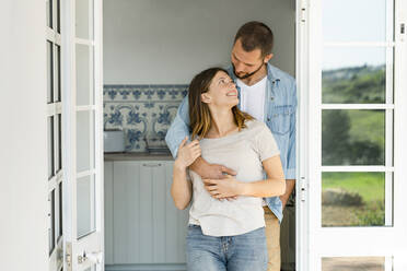 Attractive young couple standing in the door together at home and smiling at each other - SBOF02208