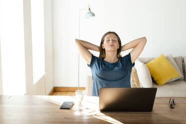 Junge Frau, die sich zu Hause entspannt und eine Pause von der Arbeit am Laptop im Home Office einlegt - SBOF02227