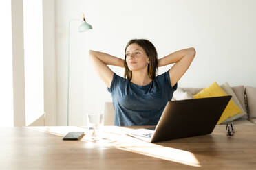 Zufriedene junge Frau zu Hause, die eine Pause von der Arbeit am Laptop im Home Office macht - SBOF02228