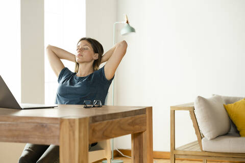 Young woman at home relaxing and having a break from working at laptop in home office stock photo