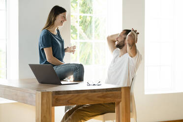 Happy couple with laptop in home office in modern living room - SBOF02236