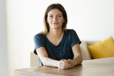 Portrait of confident young woman sitting at table at home - SBOF02239