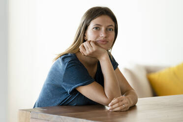 https://us.images.westend61.de/0001351443j/portrait-of-confident-young-woman-sitting-at-table-at-home-SBOF02241.jpg