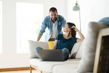 Young couple on couch at home with laptop - SBOF02244