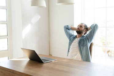 Seriöser junger Mann mit Laptop im Büro zu Hause, der eine Pause macht - SBOF02250