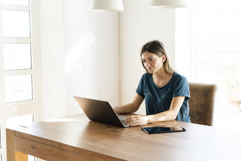 Junge Frau arbeitet zu Hause an ihrem Laptop im Heimbüro - SBOF02253