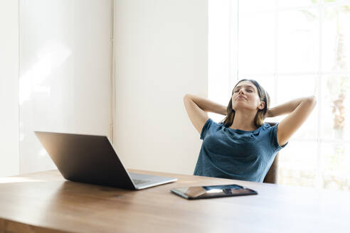 Junge Frau mit Laptop im Büro zu Hause, die eine Pause macht - SBOF02255