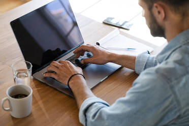 Close-up of young man at home working on his laptop in home office - SBOF02263