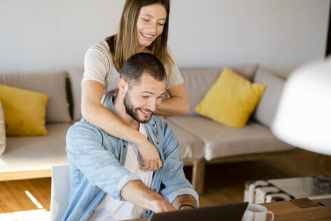 Happy young couple using laptop at home stock photo