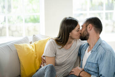 Verliebtes junges Paar küsst sich auf der Couch zu Hause - SBOF02282