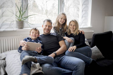 Portrait of happy family relaxing on couch at home - HMEF00841