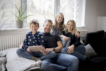 Porträt einer glücklichen Familie, die sich zu Hause auf der Couch entspannt - HMEF00842