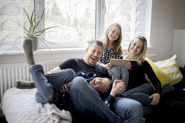 Portrait of happy family having fun on couch at home - HMEF00844