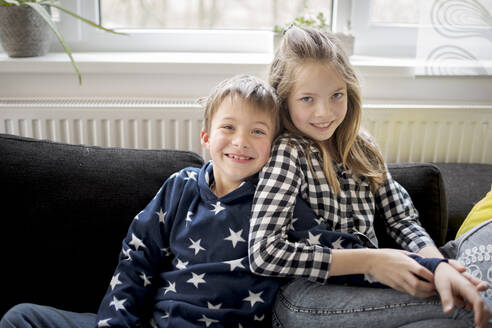 Portrait of happy boy and girl relaxing on couch at home - HMEF00848