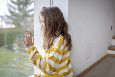 Mädchen zu Hause schaut aus dem Fenster - HMEF00854