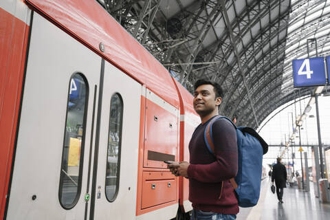 Mann mit Smartphone am Bahnhof, lizenzfreies Stockfoto