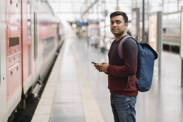 Mann mit Smartphone am Bahnhof - AHSF02105