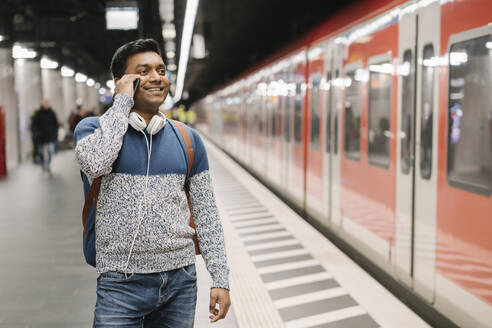 Lächelnder Mann am Telefon in einer U-Bahn-Station - AHSF02110