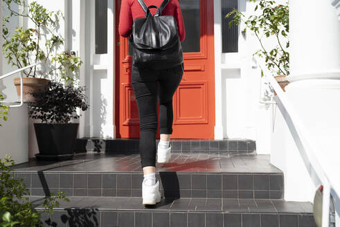 Young woman arriving at front door - FBAF01353