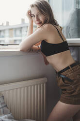 Porträt einer attraktiven jungen Frau in Dessous am Fenster - FBAF01379