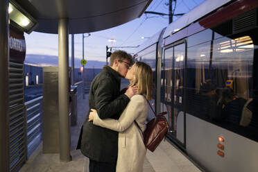 Küssendes junges Paar an der Straßenbahnhaltestelle am Abend - FBAF01384