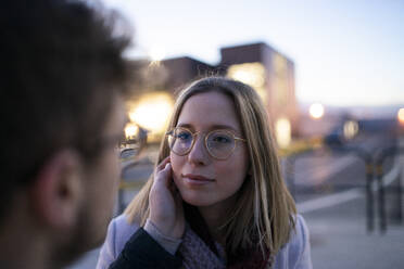 Porträt einer blonden jungen Frau von Angesicht zu Angesicht mit ihrem Freund in der Abenddämmerung - FBAF01385