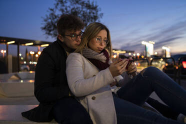 Junges Paar benutzt Smartphone in der Abenddämmerung - FBAF01388