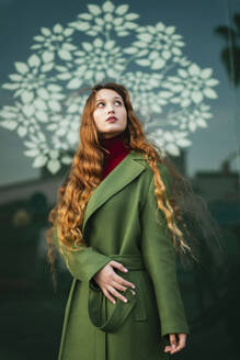 Porträt einer rothaarigen jungen Frau mit modischem grünem Mantel, die nach oben schaut - TCEF00347