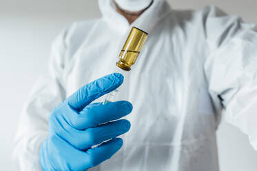 Labortechniker in Schutzkleidung, mit Impfstoff in der Hand - JCMF00522