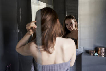 Mirror image of girl watching herself in bathroom - AUF00235