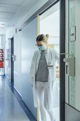 Doctor standing on hospital hallway - MFF05238