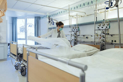 Doctor preparing bed in hospital room - MFF05245