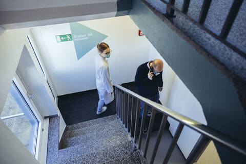 Arzt und Mann am Telefon im Treppenhaus, lizenzfreies Stockfoto