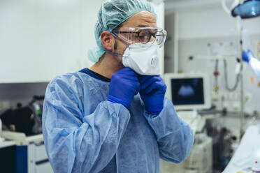 Doctor putting on ffp2 mask in emergency room of a hospital - MFF05261