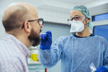 Arzt im Krankenhaus nimmt einen Abstrich aus dem Mund eines Patienten - MFF05265