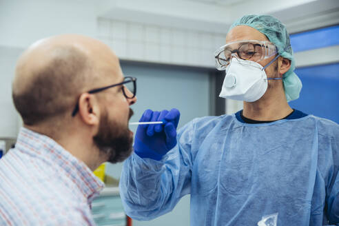 Doctor in hospital taking a swab from patient's mouth - MFF05268