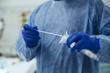 Close-up of emergeny doctor putting a swab into a tube in hospital - MFF05270