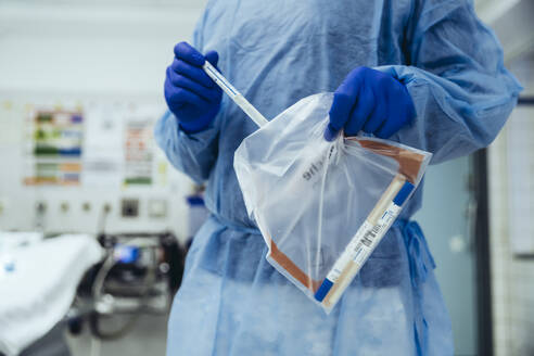 Close-up of emergeny doctor putting a swab into a plastic bag in hospital - MFF05273