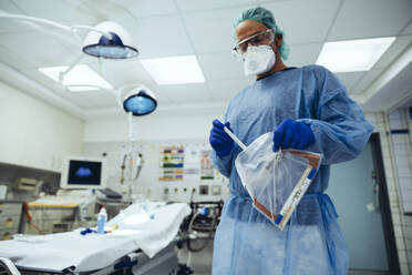 Ein Notarzt, der im Krankenhaus einen Tupfer in einen Plastikbeutel steckt - MFF05274