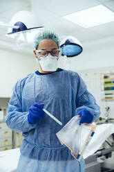 Ein Notarzt, der im Krankenhaus einen Tupfer in einen Plastikbeutel steckt - MFF05275