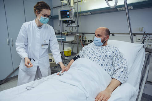 Arzt schließt Patient im Krankenhauszimmer an Pulsmesser an - MFF05302