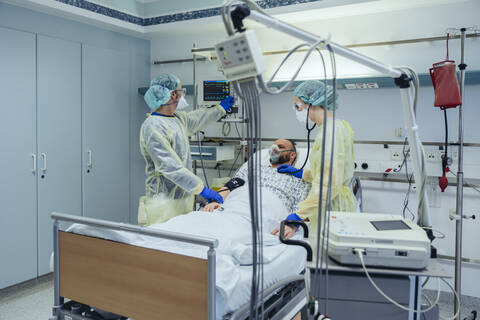 Doctors caring for patient in emergency care unit of a hospital looking at screen stock photo