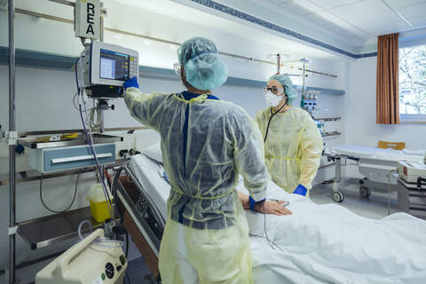 Ärzte, die sich um einen Patienten in der Notaufnahme eines Krankenhauses kümmern, schauen auf einen Bildschirm, lizenzfreies Stockfoto