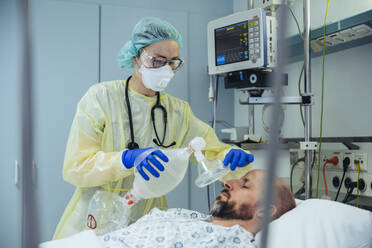 Doctor with bag valve mask caring for patient in emergency care unit of a hospital - MFF05329