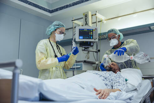 Ärzte mit Beatmungsmaske versorgen einen Patienten in der Notaufnahme eines Krankenhauses - MFF05332