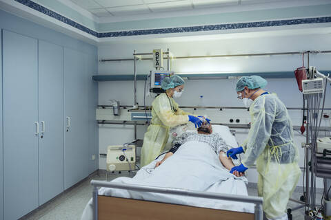 Ärzte, die sich um einen Patienten in der Notaufnahme eines Krankenhauses kümmern, wechseln von einer Sauerstoffmaske zu einer Beatmungsmaske, lizenzfreies Stockfoto