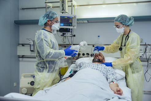 Ärzte, die sich um einen Patienten in der Notaufnahme eines Krankenhauses kümmern, wechseln von einer Sauerstoffmaske zu einer Beatmungsmaske - MFF05339